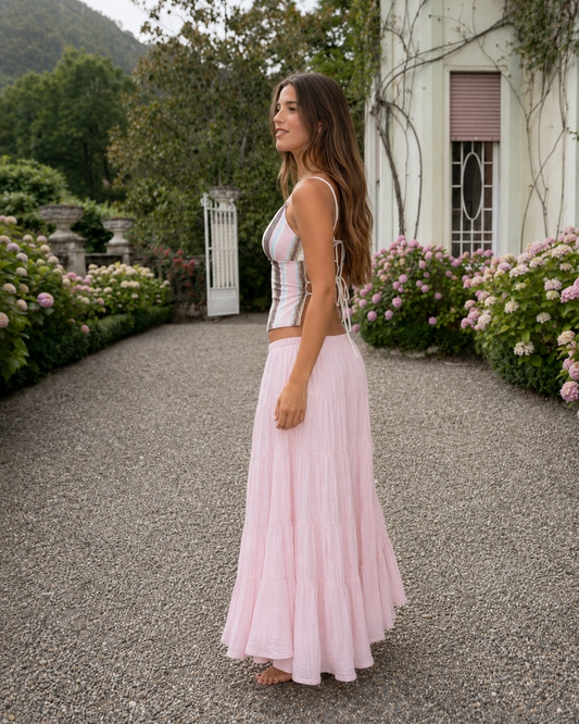 Side view of a women's striped corset cami top with blush pink tiered maxi skirt set