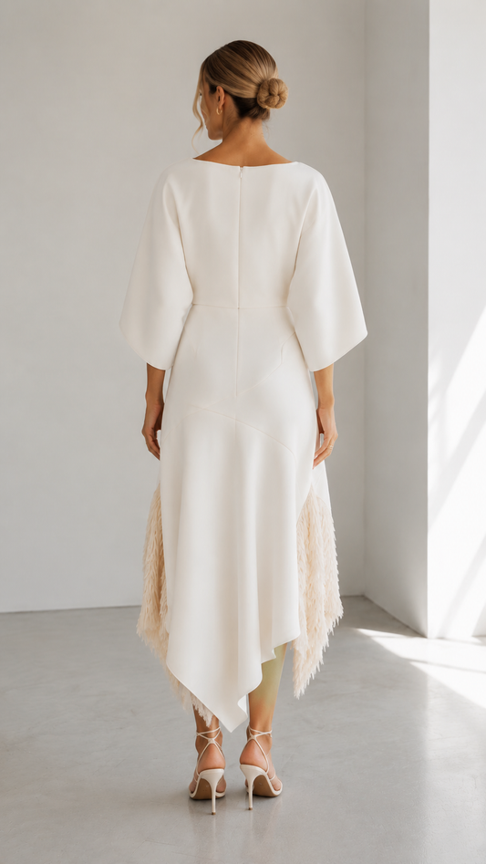 Back view of ivory asymmetric midi dress with cape sleeves and textured fringe hem