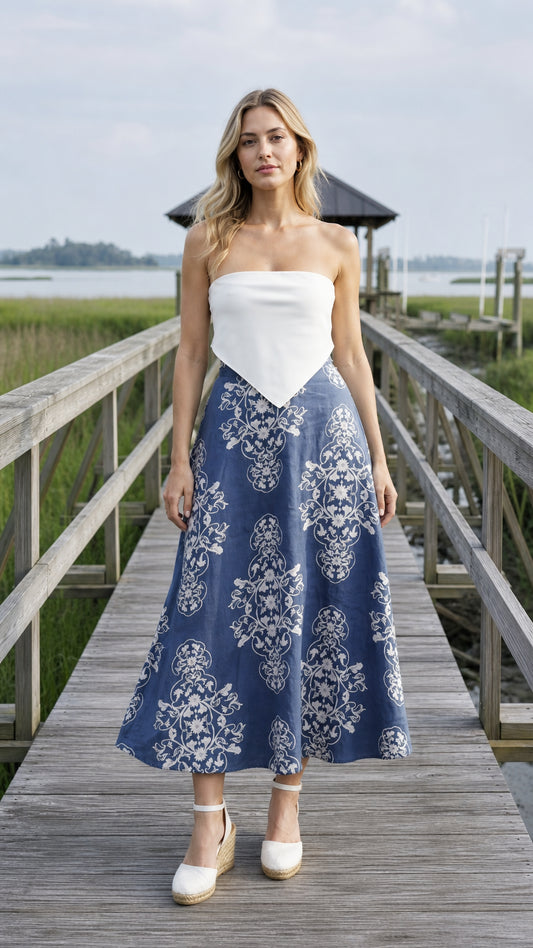 Front view of blue floral midi skirt paired with white top on wooden dock