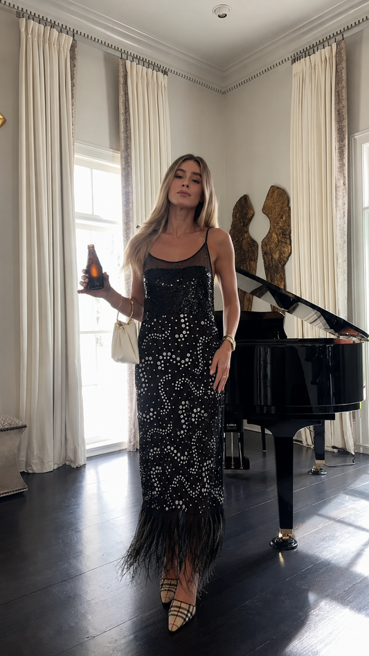 Front view of black sequin maxi slip dress with embellished pattern and black feather hem