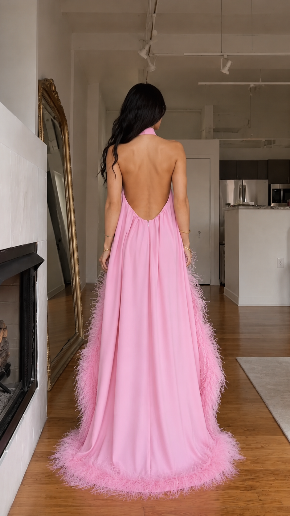 Back view of pink halter maxi dress with dramatic open back and feather-trim hem
