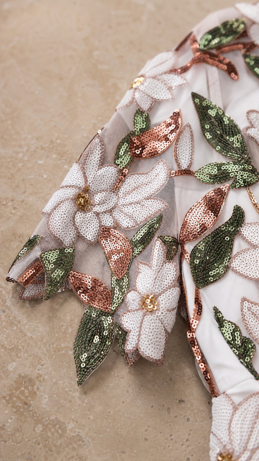 Close-up detail of white mesh fabric with floral embroidery and sequins