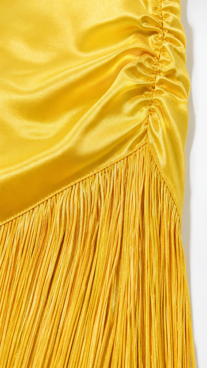 Close-up detail of smooth satin fabric, ruching, and fringe hem