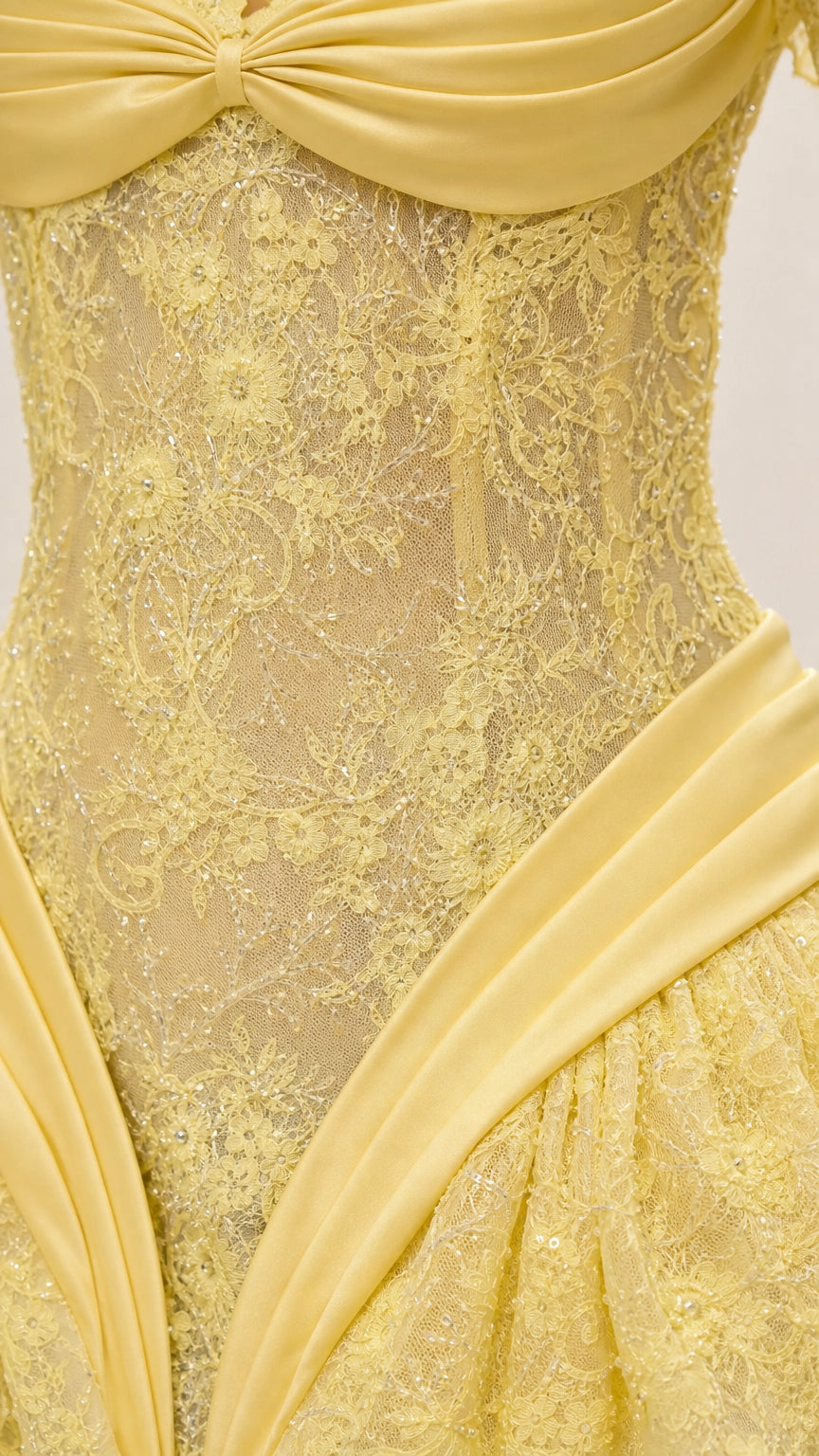 Close-up detail of lace texture and satin drape on yellow dress