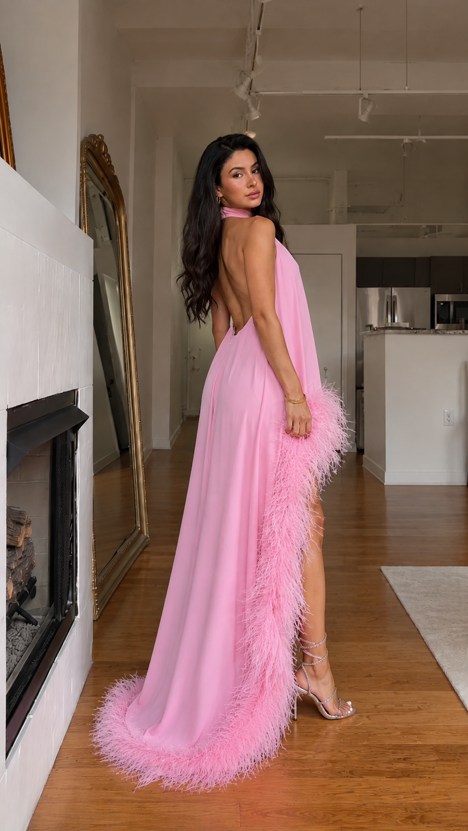Angled back view of pink open-back maxi dress with feather trim train effect