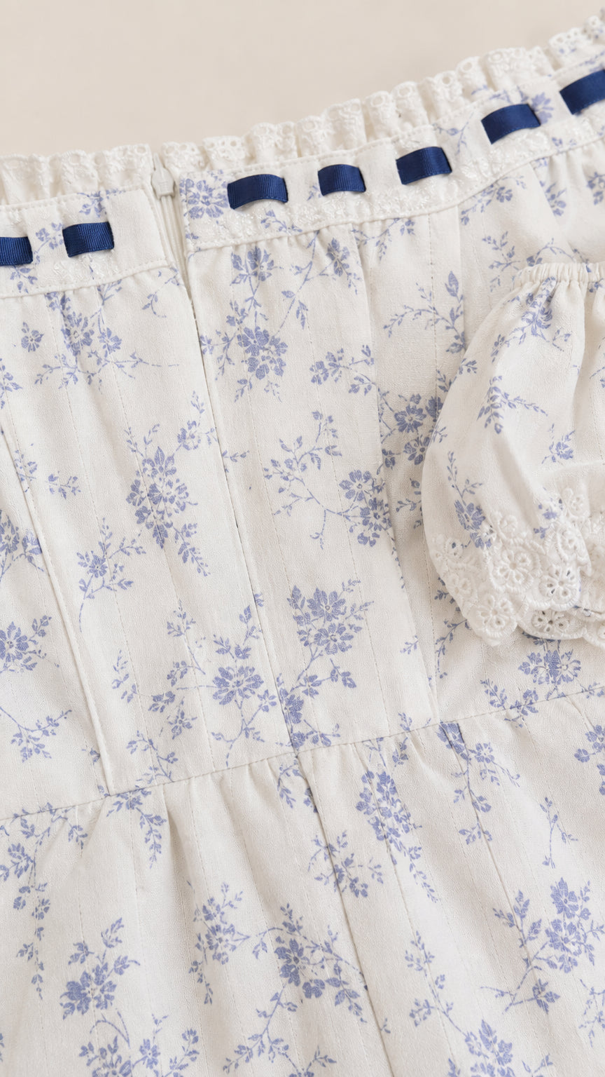 Close up of bodice details and ribbon trim on white floral dress