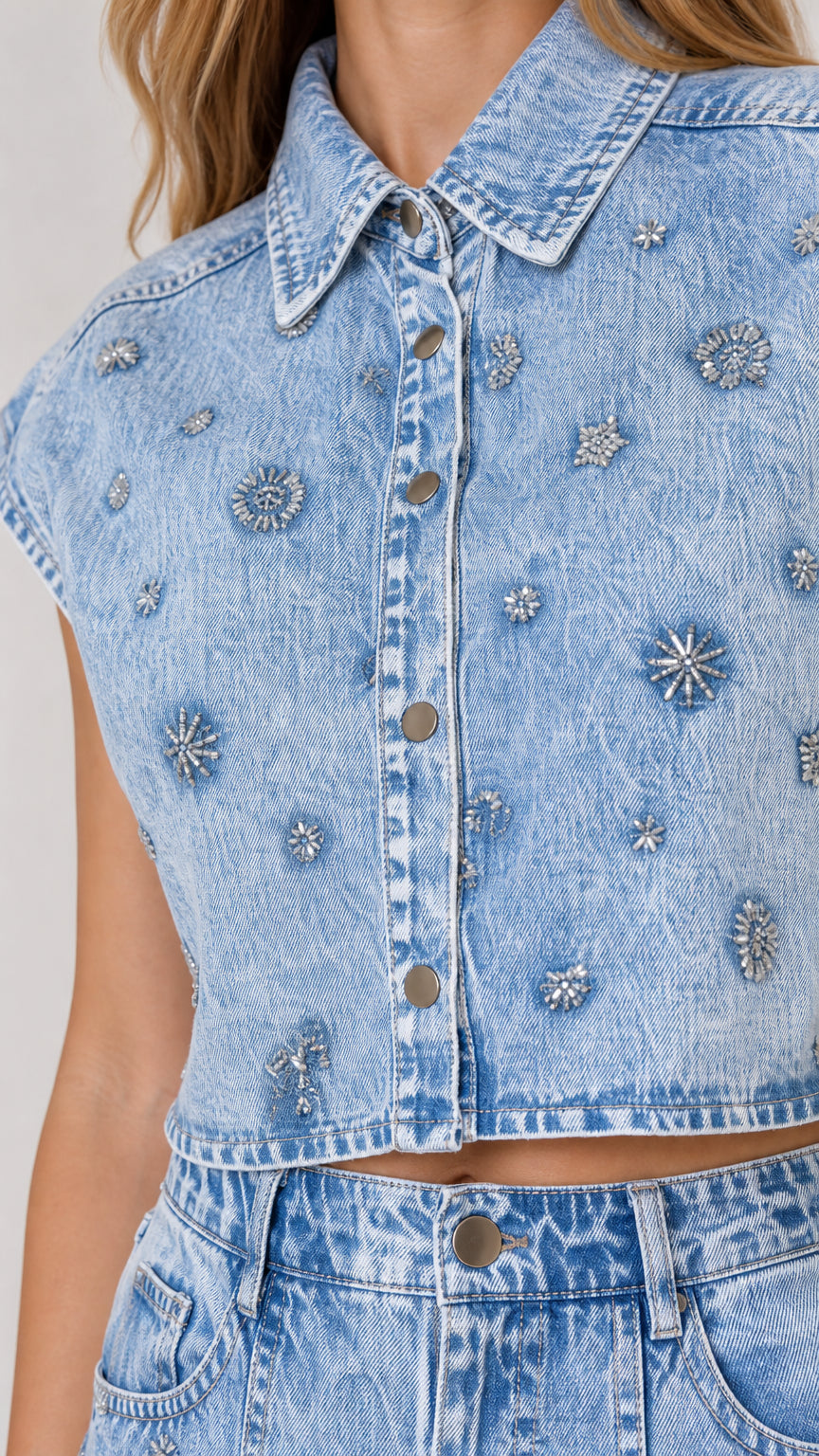 Close-up detail of rhinestone floral pattern on light blue denim button-up vest