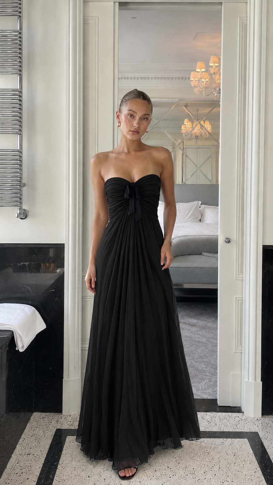 Front view of black strapless pleated maxi gown with black bow detail