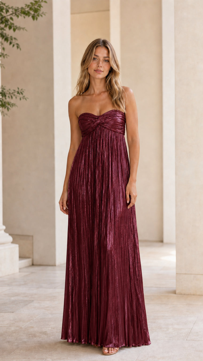 Front view of model wearing burgundy metallic pleated strapless maxi dress